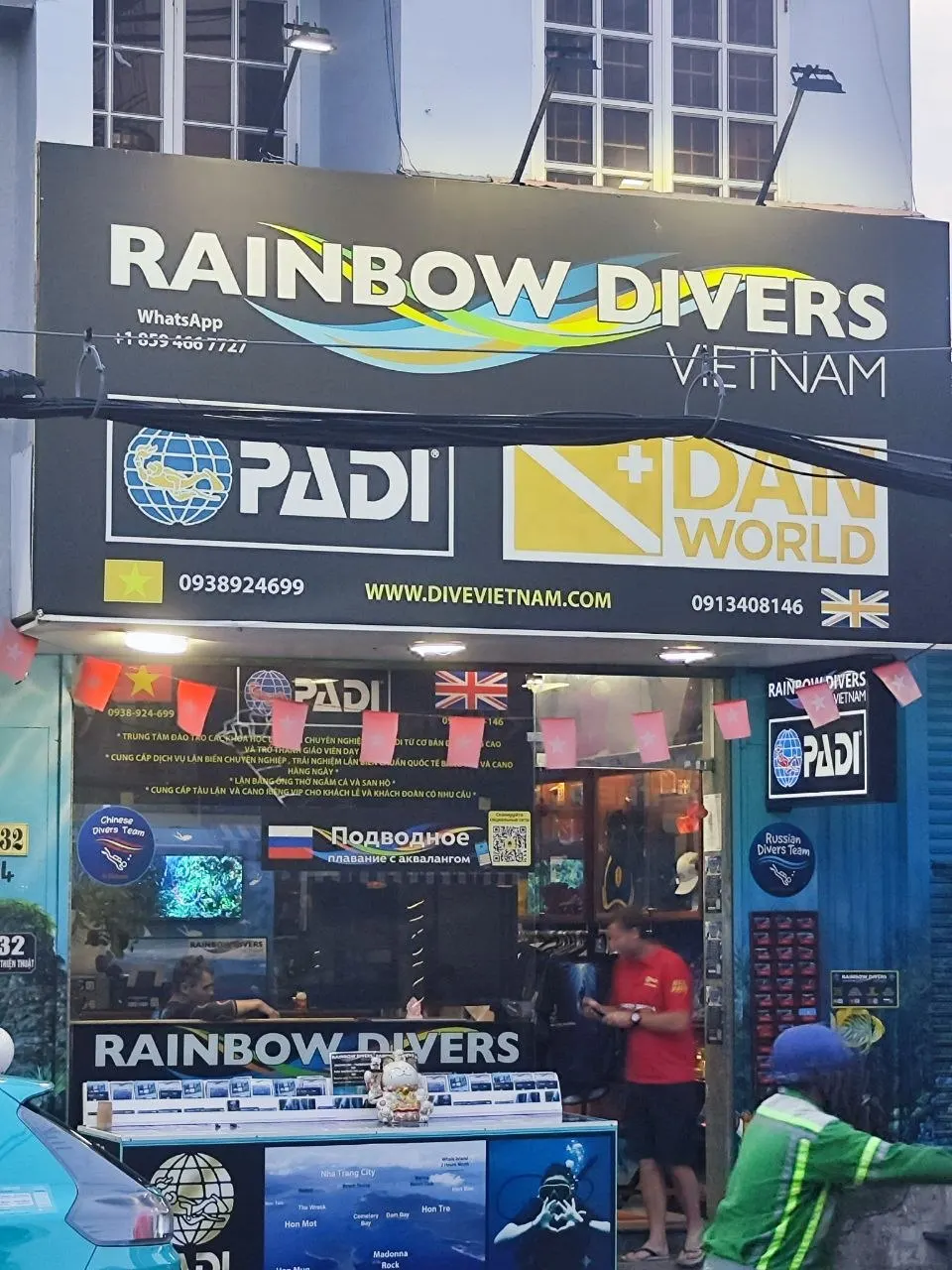 Bảng hiệu trung tâm lặn Rainbow Divers trên đường Nguyễn Thiện Thuật: logo PADI và DAN, số điện thoại 0938 924 699 và 0913 408 146, website divevietnam.com; trên kính có biển quảng cáo lặn bằng tiếng Nga